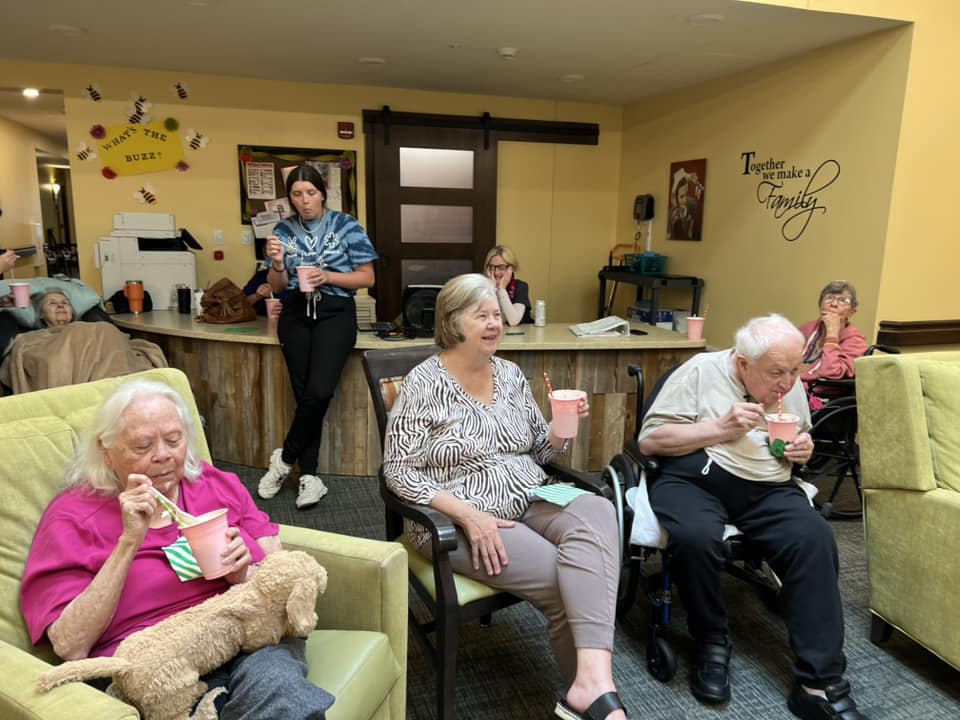 Females looking at elderly man playing with dog at retirement community nursing home